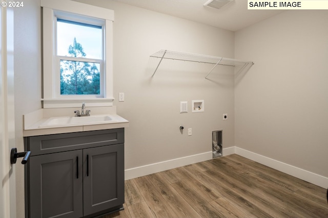 clothes washing area with hardwood / wood-style flooring, washer hookup, hookup for an electric dryer, and sink