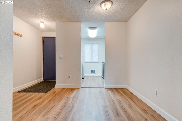 empty room with light hardwood / wood-style floors and a textured ceiling