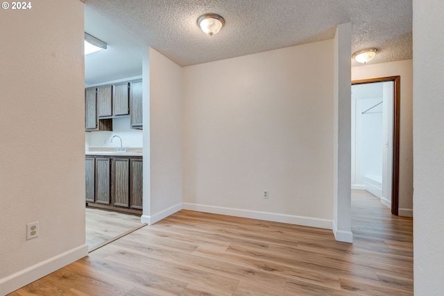 interior space with sink, a textured ceiling, and light wood-type flooring