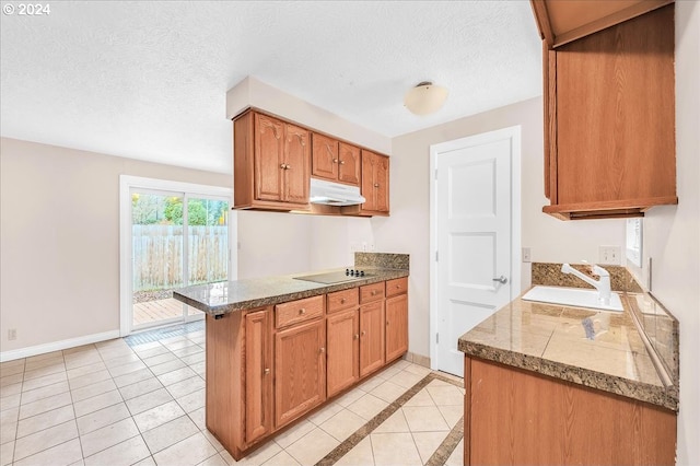 kitchen with a textured ceiling, black electric stovetop, sink, and light tile patterned flooring