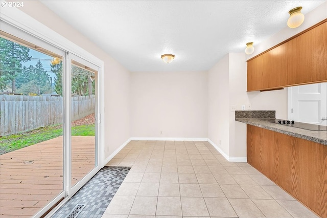 kitchen featuring a textured ceiling, light tile patterned floors, and black electric stovetop