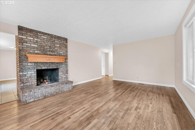 unfurnished living room with hardwood / wood-style floors, a fireplace, and a textured ceiling