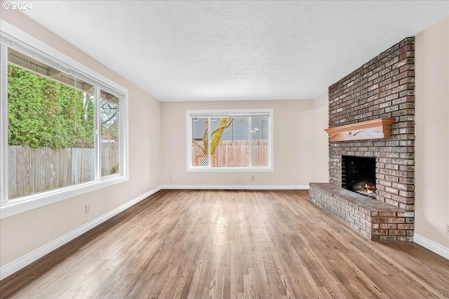 unfurnished living room with a fireplace, wood-type flooring, and a textured ceiling