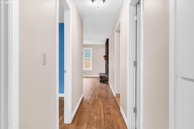 corridor featuring a textured ceiling and hardwood / wood-style flooring