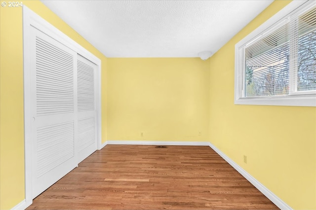 unfurnished bedroom featuring a closet, a textured ceiling, and light hardwood / wood-style floors