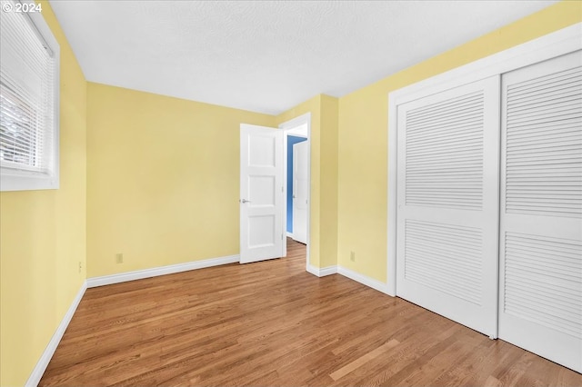 unfurnished bedroom featuring hardwood / wood-style flooring, a textured ceiling, and a closet