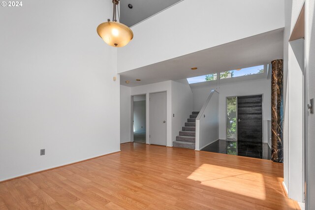 unfurnished living room featuring a towering ceiling and light hardwood / wood-style flooring