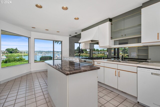 kitchen featuring white dishwasher, sink, a kitchen island, and white cabinets