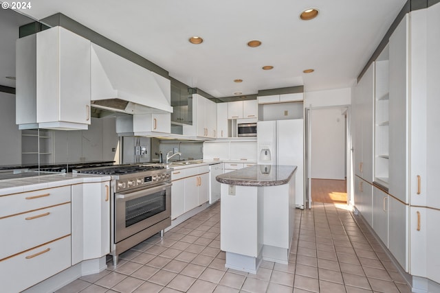 kitchen featuring sink, a center island, light tile patterned floors, appliances with stainless steel finishes, and white cabinets