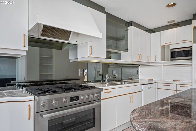 kitchen featuring light tile patterned flooring, exhaust hood, white cabinets, and appliances with stainless steel finishes