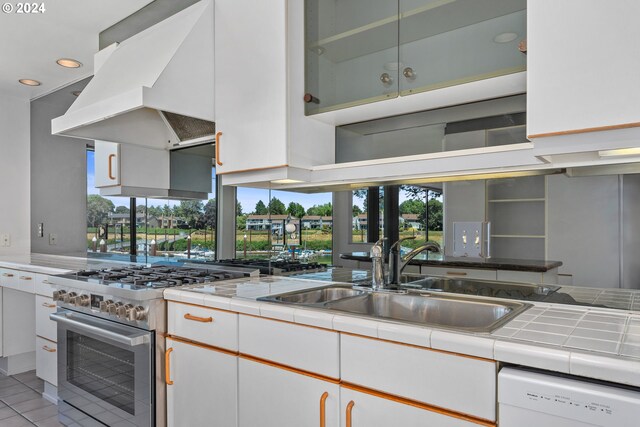 kitchen featuring light tile patterned floors, sink, stainless steel appliances, extractor fan, and white cabinets