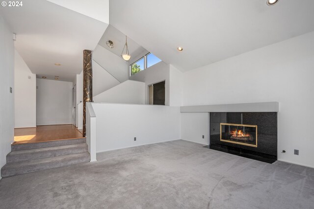 unfurnished living room with high vaulted ceiling, carpet floors, and a tile fireplace