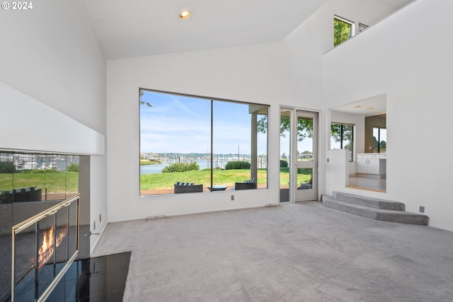 living room featuring a water view, high vaulted ceiling, and carpet floors