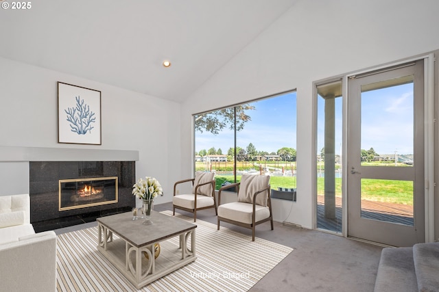 living room with a water view, a tiled fireplace, high vaulted ceiling, and carpet