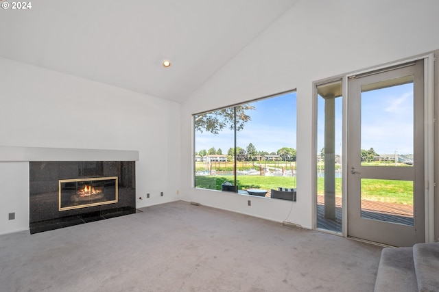 unfurnished living room featuring a tiled fireplace, plenty of natural light, high vaulted ceiling, and carpet