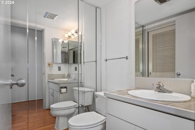 bathroom with hardwood / wood-style flooring, vanity, toilet, and an inviting chandelier