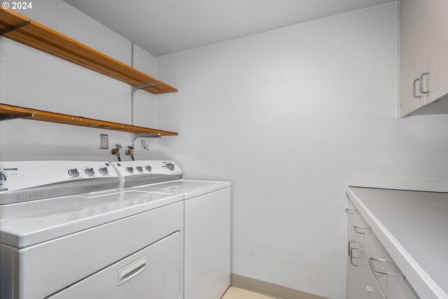 washroom featuring cabinets and washer and clothes dryer