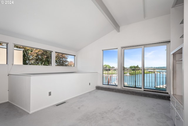 carpeted empty room featuring a water view and vaulted ceiling with beams