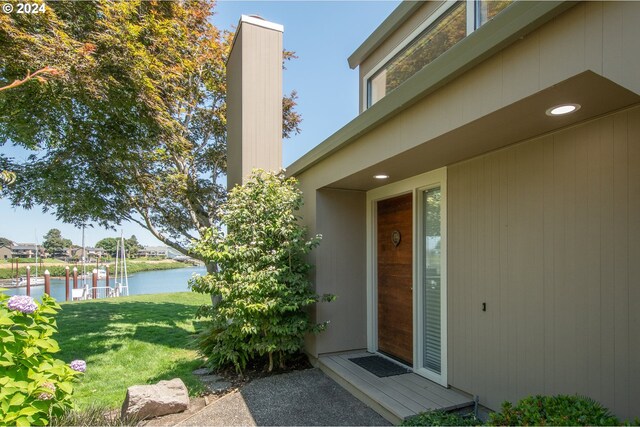 entrance to property featuring a lawn and a water view