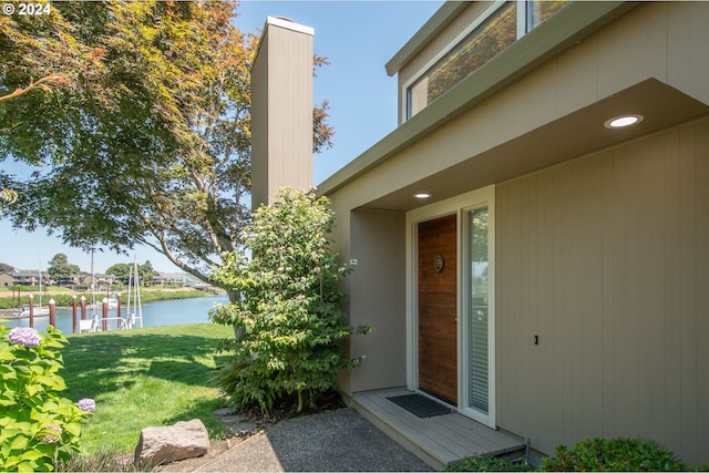 view of exterior entry with a lawn and a water view