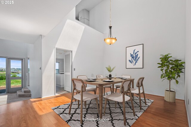 dining space featuring wood-type flooring and a high ceiling