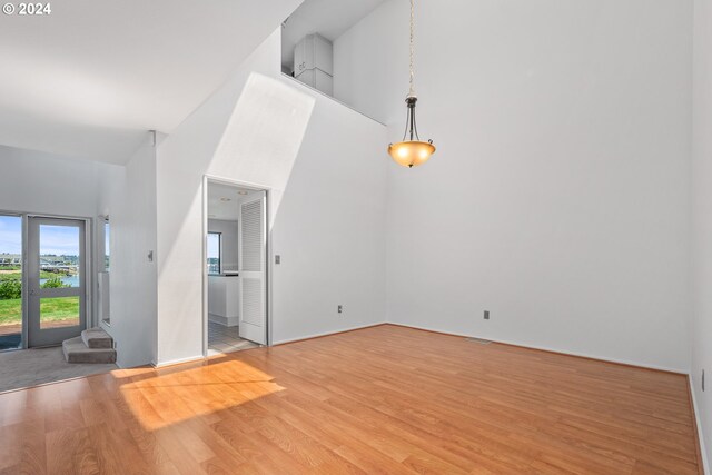 unfurnished living room featuring a towering ceiling and light wood-type flooring