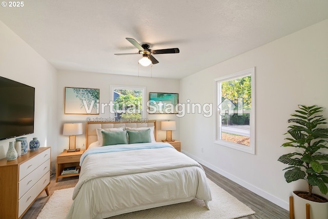 bedroom featuring ceiling fan, dark wood-type flooring, multiple windows, and a textured ceiling