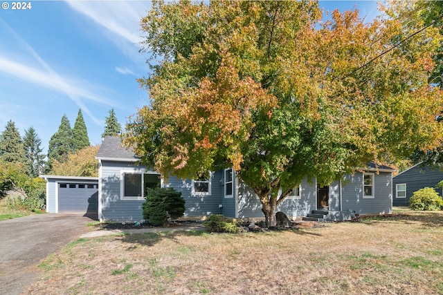 view of property hidden behind natural elements with a front lawn and a garage