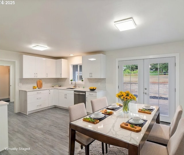 kitchen with stainless steel dishwasher, french doors, backsplash, white cabinets, and sink