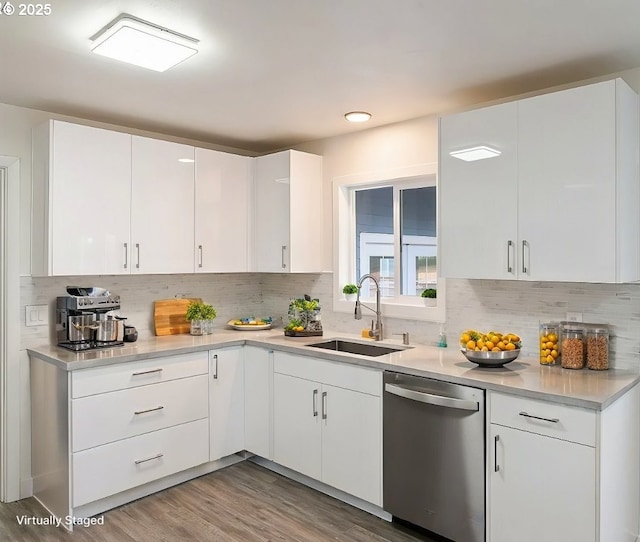 kitchen with white cabinetry, decorative backsplash, sink, light hardwood / wood-style flooring, and stainless steel dishwasher