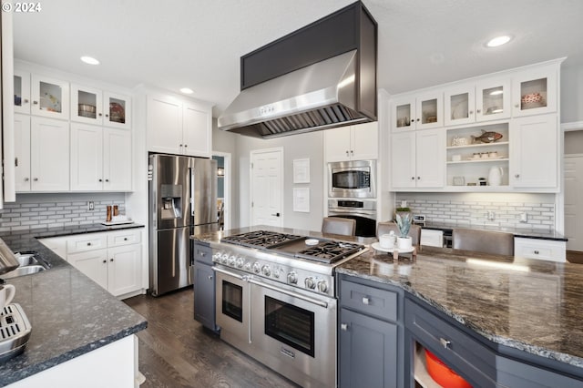 kitchen with decorative backsplash, white cabinetry, stainless steel appliances, and wall chimney range hood