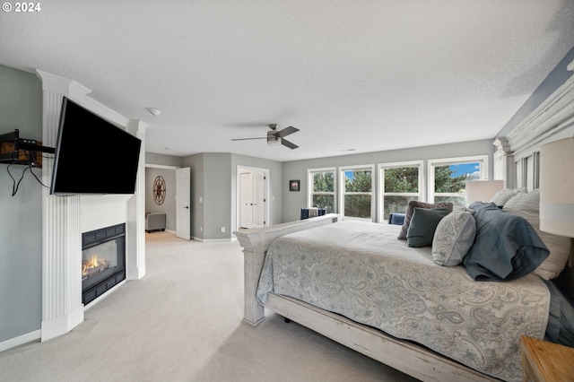 bedroom with a textured ceiling, ceiling fan, and light carpet