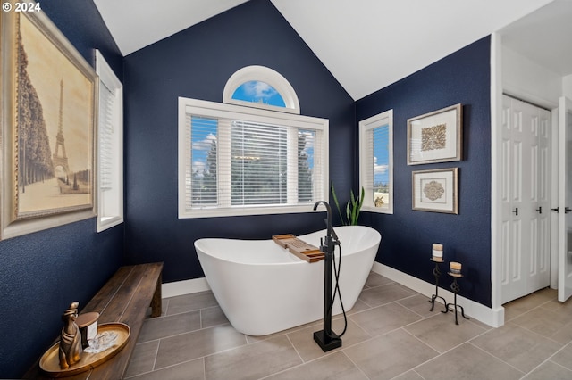 bathroom with tile patterned floors, a bathtub, and lofted ceiling