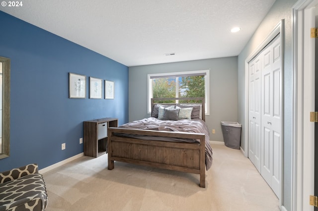 bedroom with light carpet, a textured ceiling, and a closet