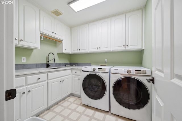 clothes washing area featuring cabinets, washer and clothes dryer, and sink