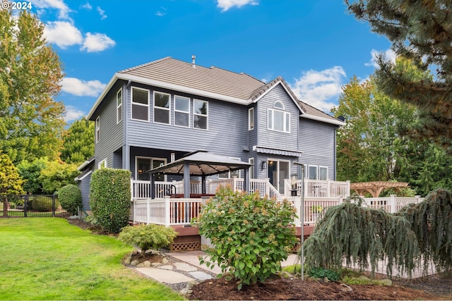 back of property with a gazebo, a wooden deck, and a lawn