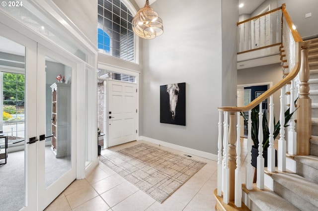 entryway featuring a high ceiling, light tile patterned floors, french doors, and a notable chandelier