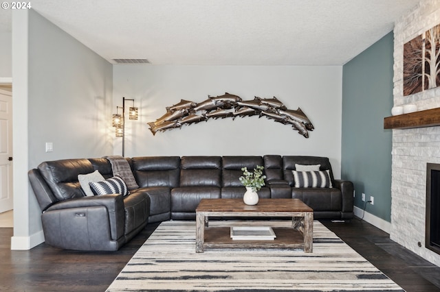 living room featuring a fireplace, a textured ceiling, and dark hardwood / wood-style floors