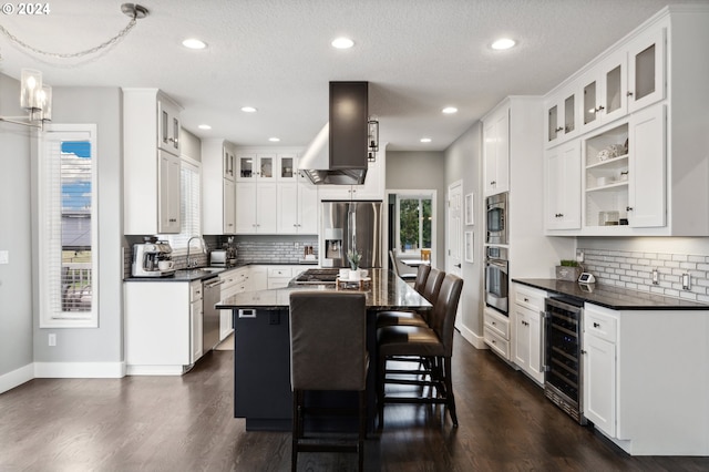 kitchen with wine cooler, stainless steel appliances, a kitchen island, and white cabinetry