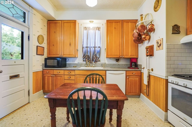 kitchen with backsplash, wood walls, sink, and white appliances