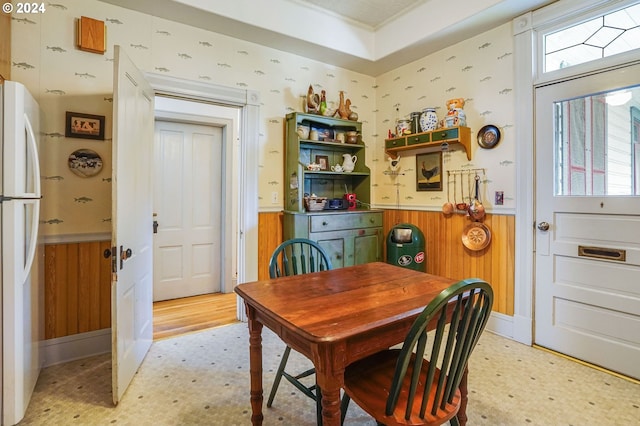 dining space featuring light wood-type flooring and wood walls