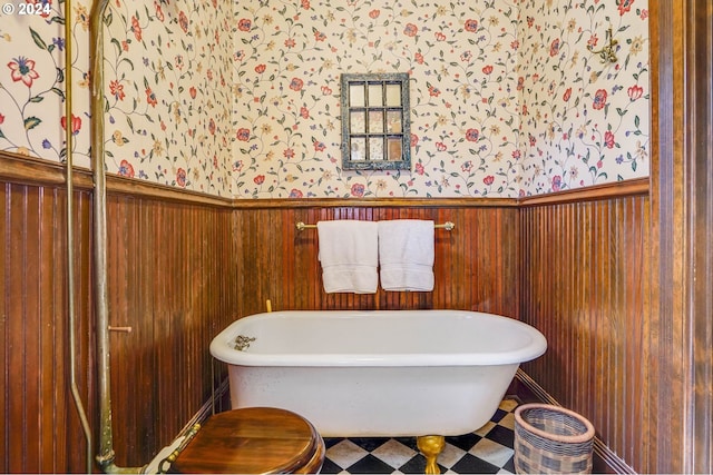 bathroom with toilet, wooden walls, and a washtub