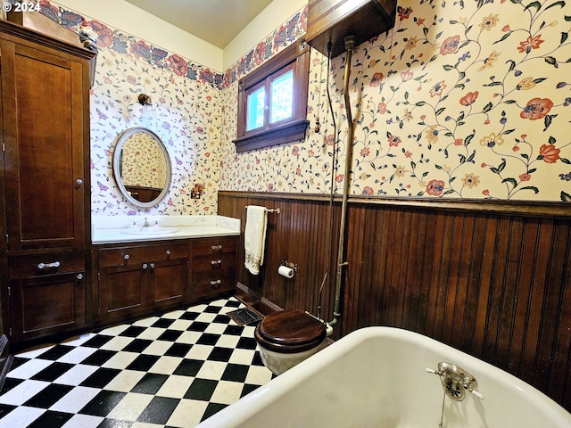 bathroom with vanity, wooden walls, toilet, and a bath