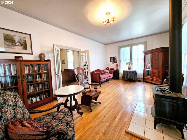 sitting room featuring light hardwood / wood-style flooring, crown molding, and a wood stove