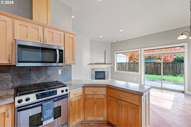 2721 La Darrah St, Eugene, OR 97404 - kitchen featuring appliances with stainless steel finishes, light brown cabinets, a peninsula, tasteful backsplash, and a tiled fireplace