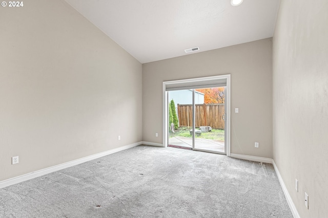 carpeted empty room featuring vaulted ceiling