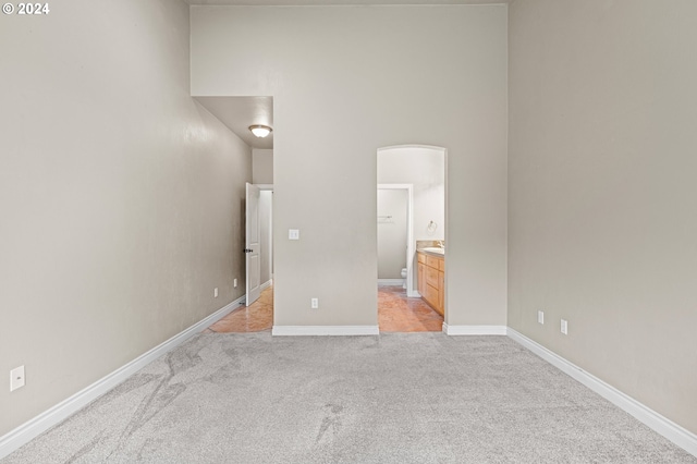 2721 La Darrah St, Eugene, OR 97404 - unfurnished bedroom with light carpet, baseboards, connected bathroom, arched walkways, and a high ceiling
