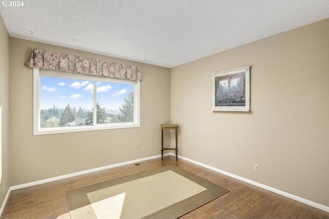 spare room with hardwood / wood-style floors and a textured ceiling