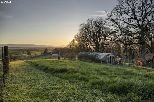 yard at dusk featuring a rural view and an outdoor structure