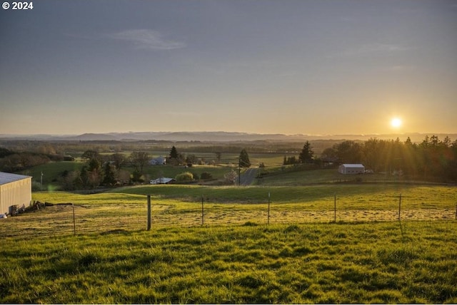 yard at dusk featuring a rural view